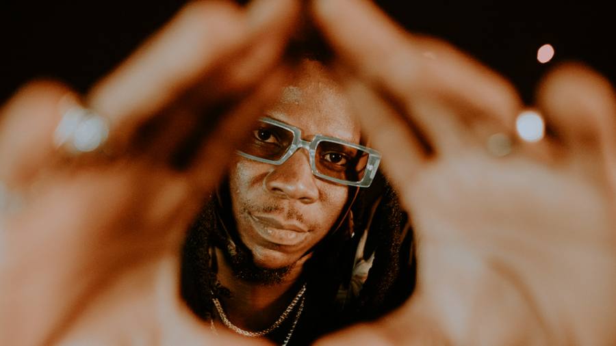 Stonebwoy framed by hands forming a pyramid gesture